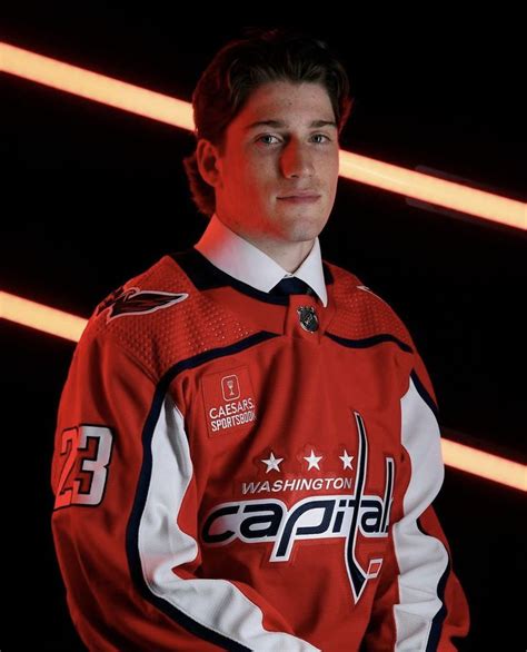 a man in a red hockey jersey is posing for a photo with his hands on ...