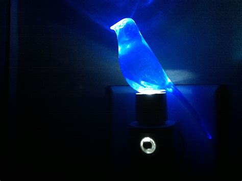 a blue light shines on the side of a wall mounted device with a bird