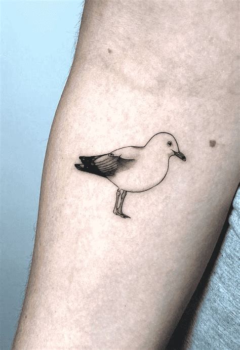 a small black and white bird tattoo on the right arm, with an outline ...