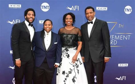 three men and a woman standing on a red carpet