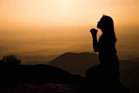 Silhouette of woman kneeling and praying over beautiful sunrise ...