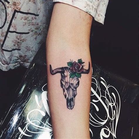 a woman's arm with a tattoo on it that has a bull skull and roses on it