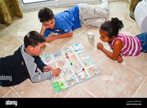 3 ethnic diversity kids boys and girl playing board game indoor United States MR ©Myrleen ...