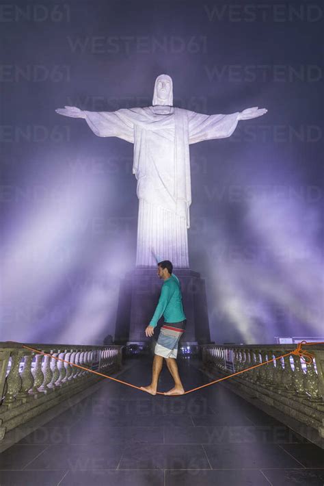 Man slacklining under Christ the Redeemer statue at night at Corcovado ...