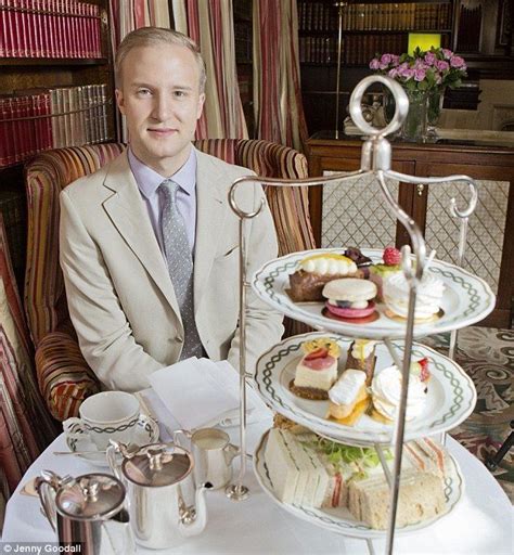 a man sitting at a table with three tiered trays of food on it