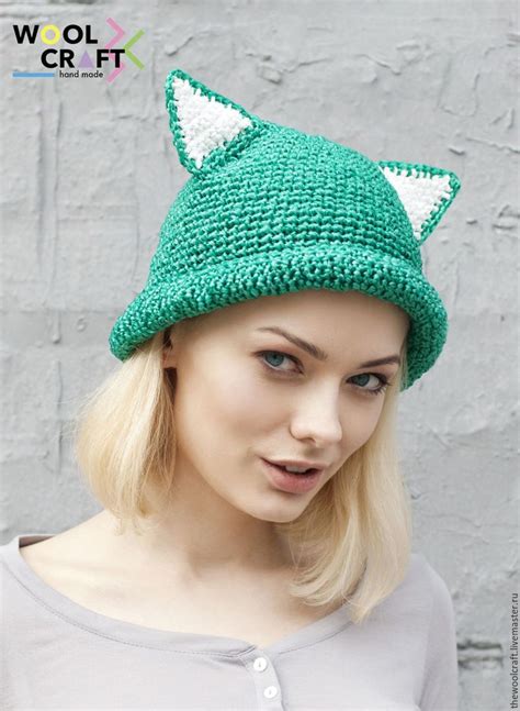 a woman wearing a green knitted hat with white cat ears