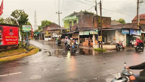 Sukoharjo - May 16, 2022 - motorcyclists pass through the wet asphalt road at the intersection ...