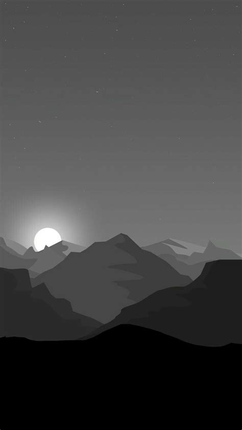 the sun is setting over the mountains in black and white, as seen from afar