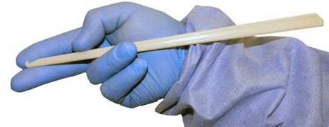 a person in blue gloves holding a white object with a wooden stick sticking out of it