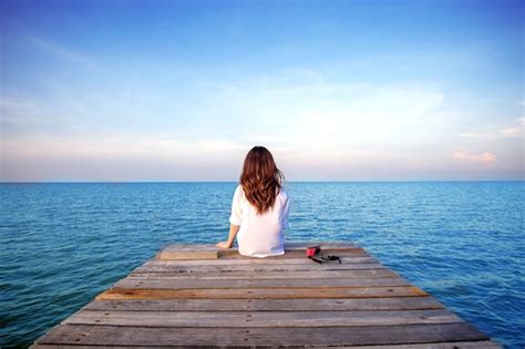 Free Photo | Girl sitting alone on a the wooden bridge on the sea. (frustrated depression)