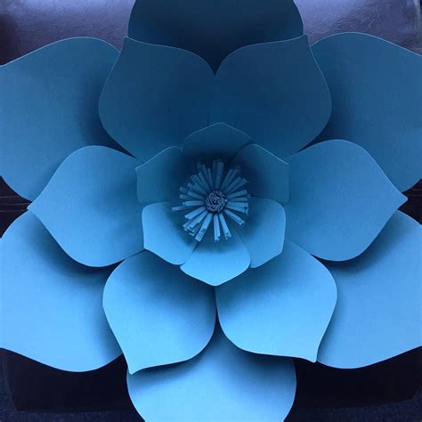 a large blue paper flower sitting on top of a black table next to a chair