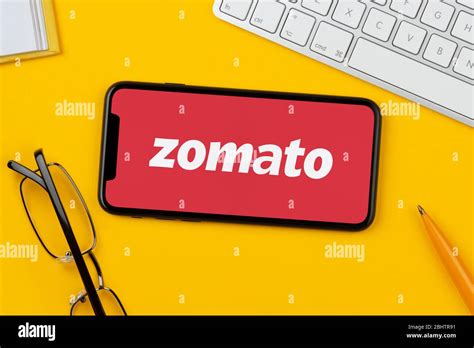 A smartphone showing the Zomato logo rests on a yellow background along ...