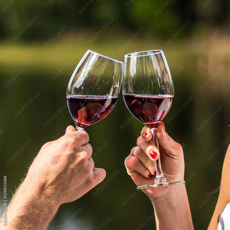 Lovers clinking wine glasses in nature for the love. Cheers! Hands holding wine glass. Green ...