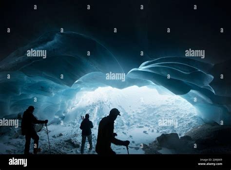 Silhouetted men hiking in glacier ice cave, Selkirk Mountains, Canada ...