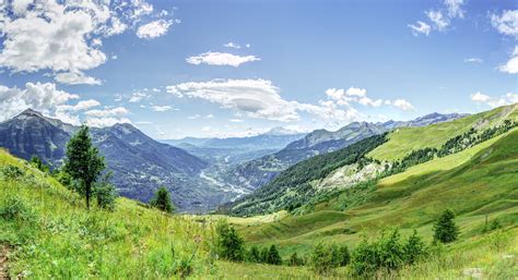 Landscape photo of green grass field and trees with mountains under nimbus cloud during daytime ...