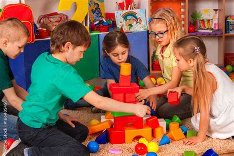 Children building blocks in kindergarten. Group kids playing toy on floor. Top view of interior ...