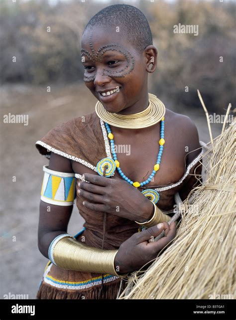 Tanzania, Northern Tanzania, Manyara. A Datoga woman relaxes outside her thatched house. The ...