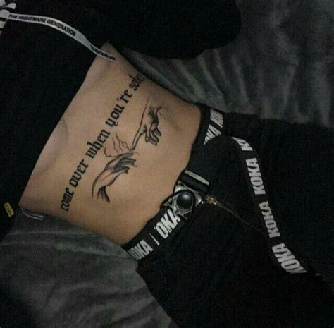 a person laying on top of a bed with tattoos on their stomach and back legs