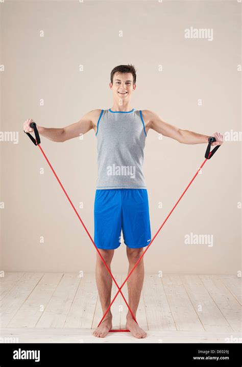 Young man doing strengthening and stretching exercises with a rubber rope Stock Photo - Alamy