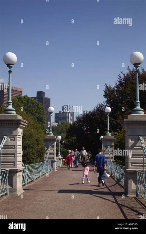 People walking over foot bridge at Boston Public Garden with city ...