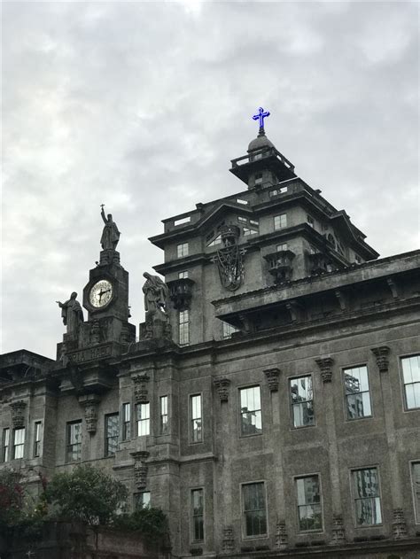 an old building with a clock on the top of it's roof and windows