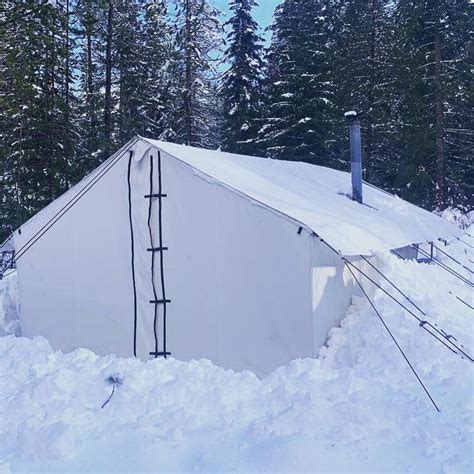 a white tent in the snow surrounded by trees