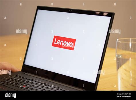 Person sitting a desk using a Lenovo laptop with the Lenovo logo on ...