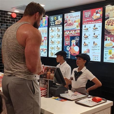 a man standing in front of a fast food restaurant counter talking to a woman at the cash register