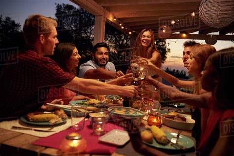 Friends make a toast at a dinner party on a patio, close up - Stock Photo - Dissolve