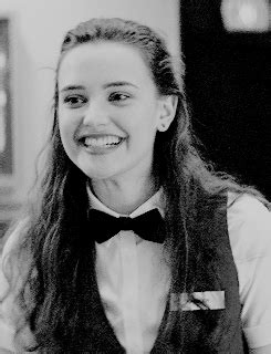 a woman with long hair wearing a vest and bow tie smiles while sitting at a table
