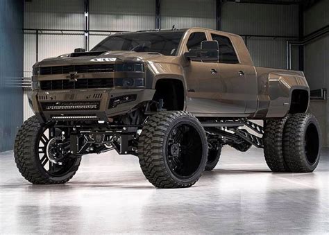 a brown truck with big tires in a garage area, on display at an automobile show