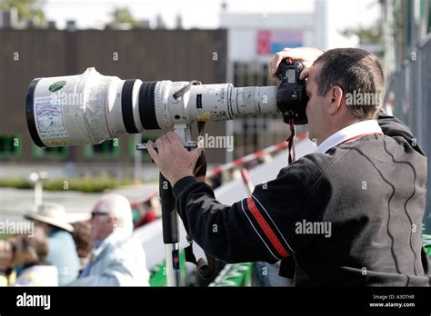 SPORTS PHOTOGRAPHER WITH A LONG CANON TELEPHOTO LENS PHOTOGRAPHING A ...