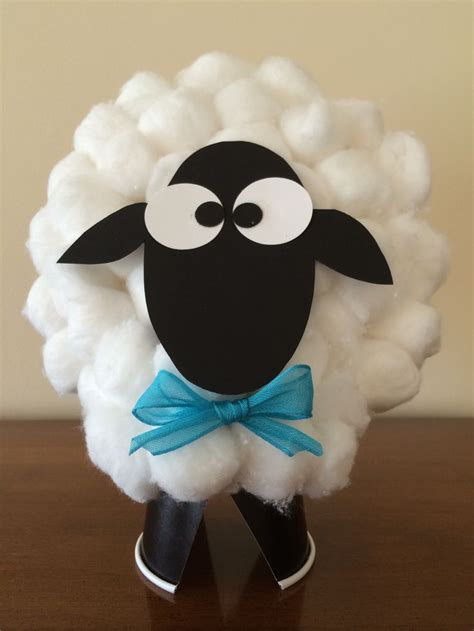 a black and white sheep with a blue bow on it's head sitting on a table