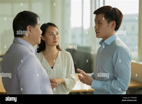 Singapore, Three people talking in office Stock Photo - Alamy