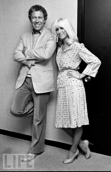 a man and woman standing next to each other in front of a wall with the door open