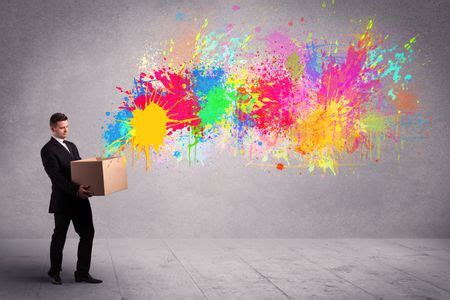 A young smiling business male holding a paperboard box with illustration of colourful spray ...