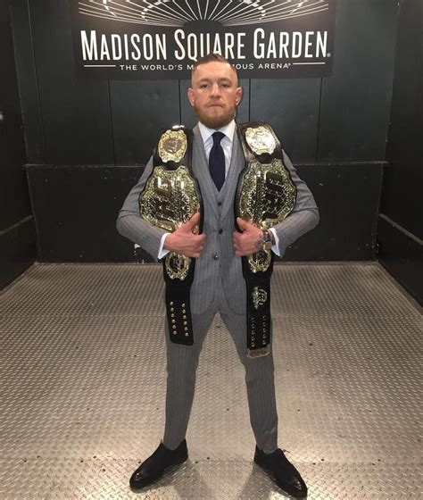 Conor McGregor poses post fight with his belts. He became the first to ...