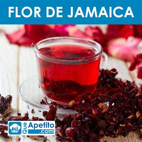 a glass cup filled with red tea next to dried rose petals on a wooden table