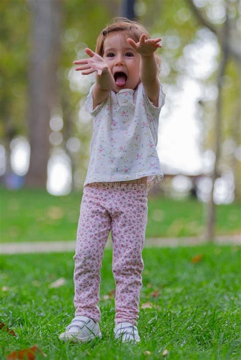 Small Girl Standing with Outstretched Hands on the Grass in the Park ...