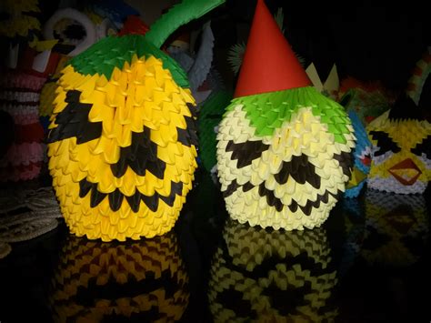 two paper pumpkins with faces on them, one is yellow and the other is green