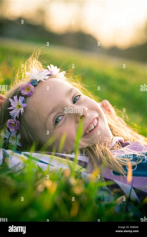 Portrait of smiling little girl lying on meadow wearing flowers Stock Photo - Alamy