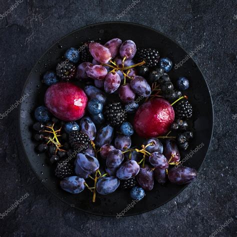 Fresh dark fruits and berries on black plate — Stock Photo © Anna_Shepulova #84492048