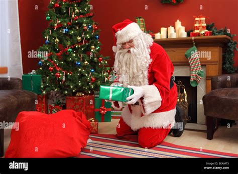 Santa Claus putting gifts under Christmas tree Stock Photo - Alamy