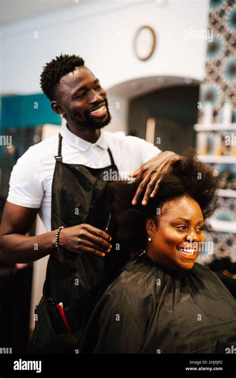 Smiling male barber cutting hair of female customer in salon Stock Photo - Alamy