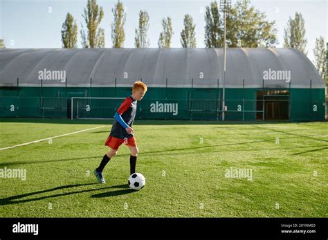 Elementary age football player kicking ball training along on soccer ...