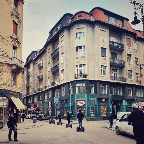 people are riding scooters in the middle of an urban area with tall buildings