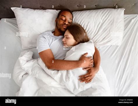 Top view of affectionate multiracial couple hugging each other while sleeping in bed Stock Photo ...