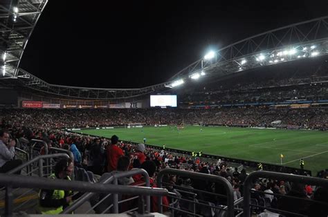 a stadium filled with lots of people watching a soccer game on the field at night