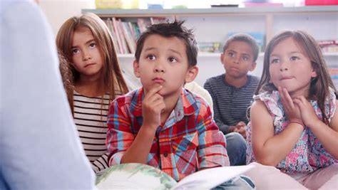 Elementary school kids listening to teacher reading a story - Stock ...