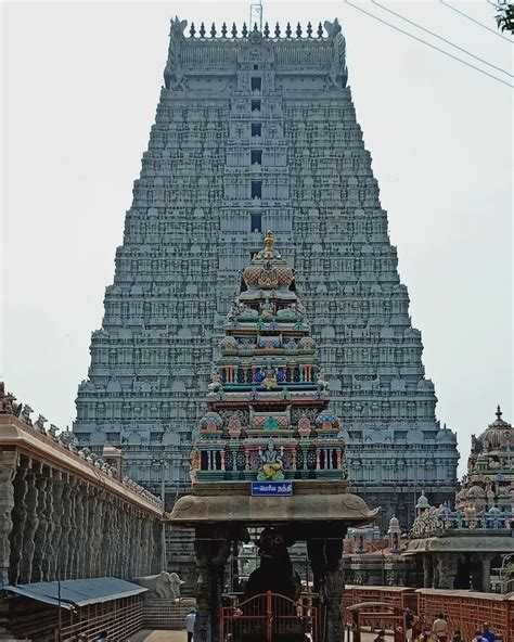 a very tall building with many statues on it's sides and people walking around